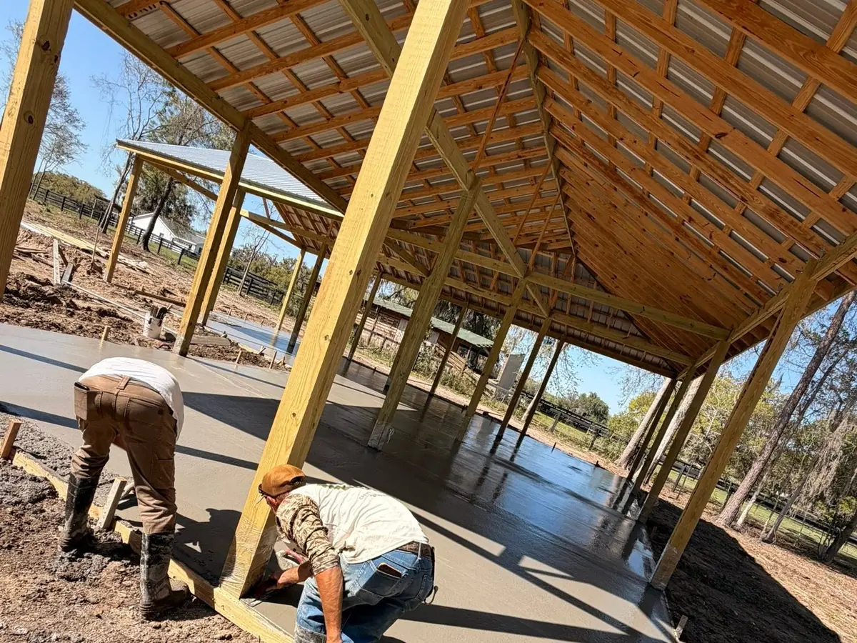 Two concrete finishers troweling a fresh slab inside a timber frame