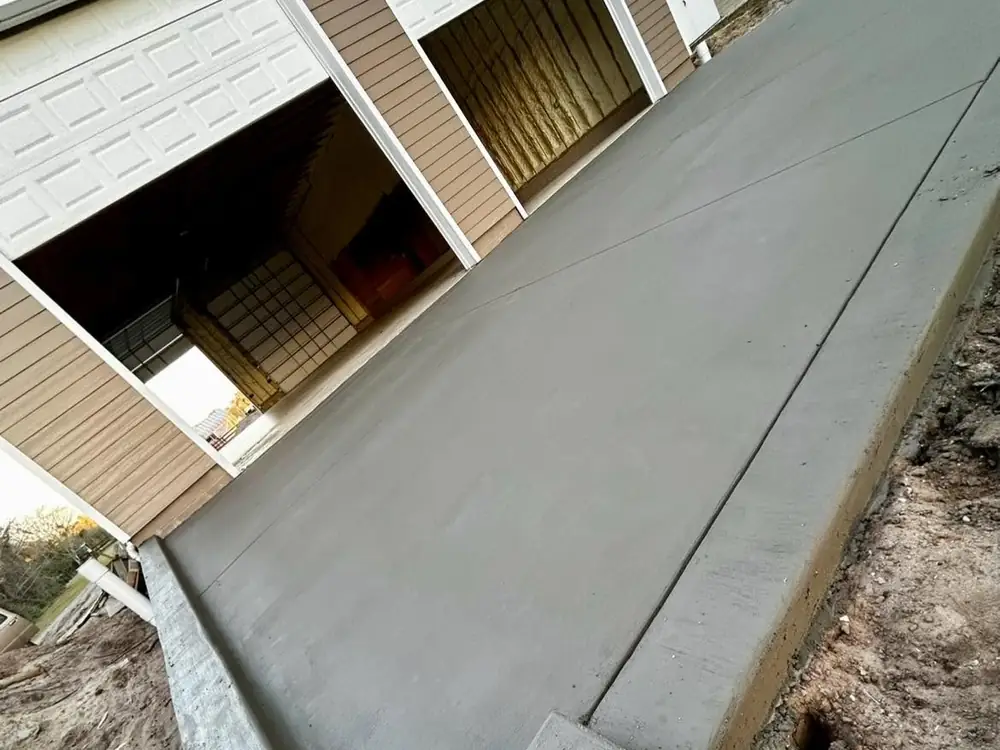 Concrete driveway apron with a thickened edge running to barn doors