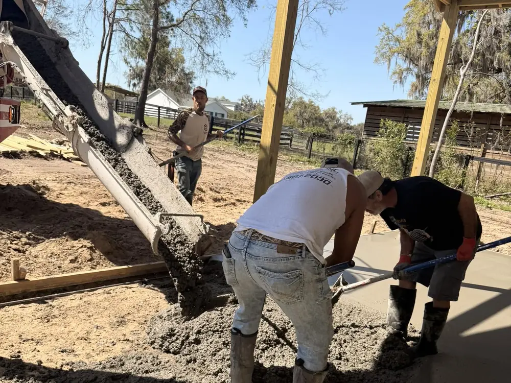 Two men placing and screeding fresh concrete between the forms